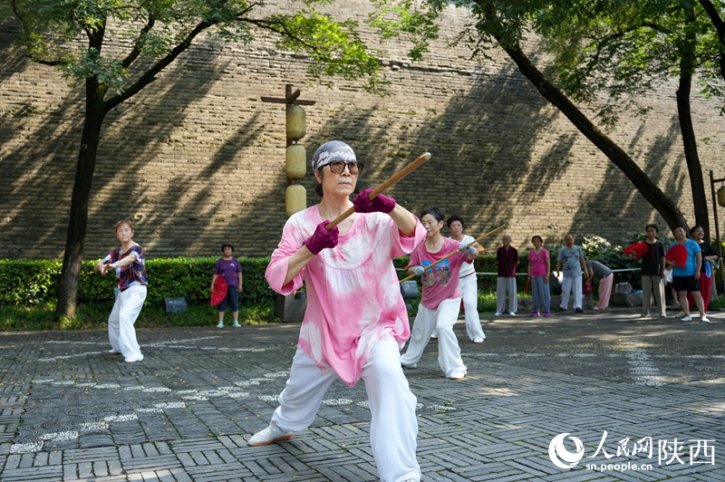 市民在西安城墻下的環(huán)城公園內(nèi)練習(xí)龍形鞭桿。李欣宇 攝